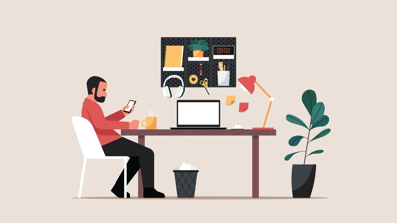 A person sits at a desk with a smartphone, beside a laptop, coffee mug, desk lamp, and potted plant. A pegboard with office supplies hangs above.