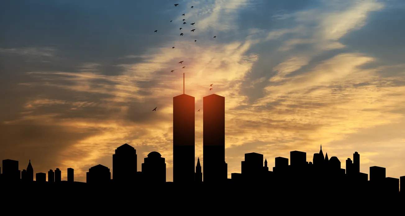 Silhouette of a city skyline at sunset, with the iconic twin towers and a flock of birds flying against a dramatic, colorful sky.