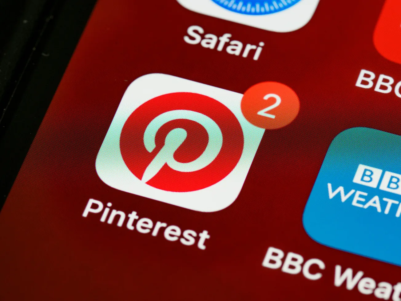 Close-up of a smartphone screen showing the Pinterest app icon with a red notification badge displaying '2.' Other app icons are partially visible.