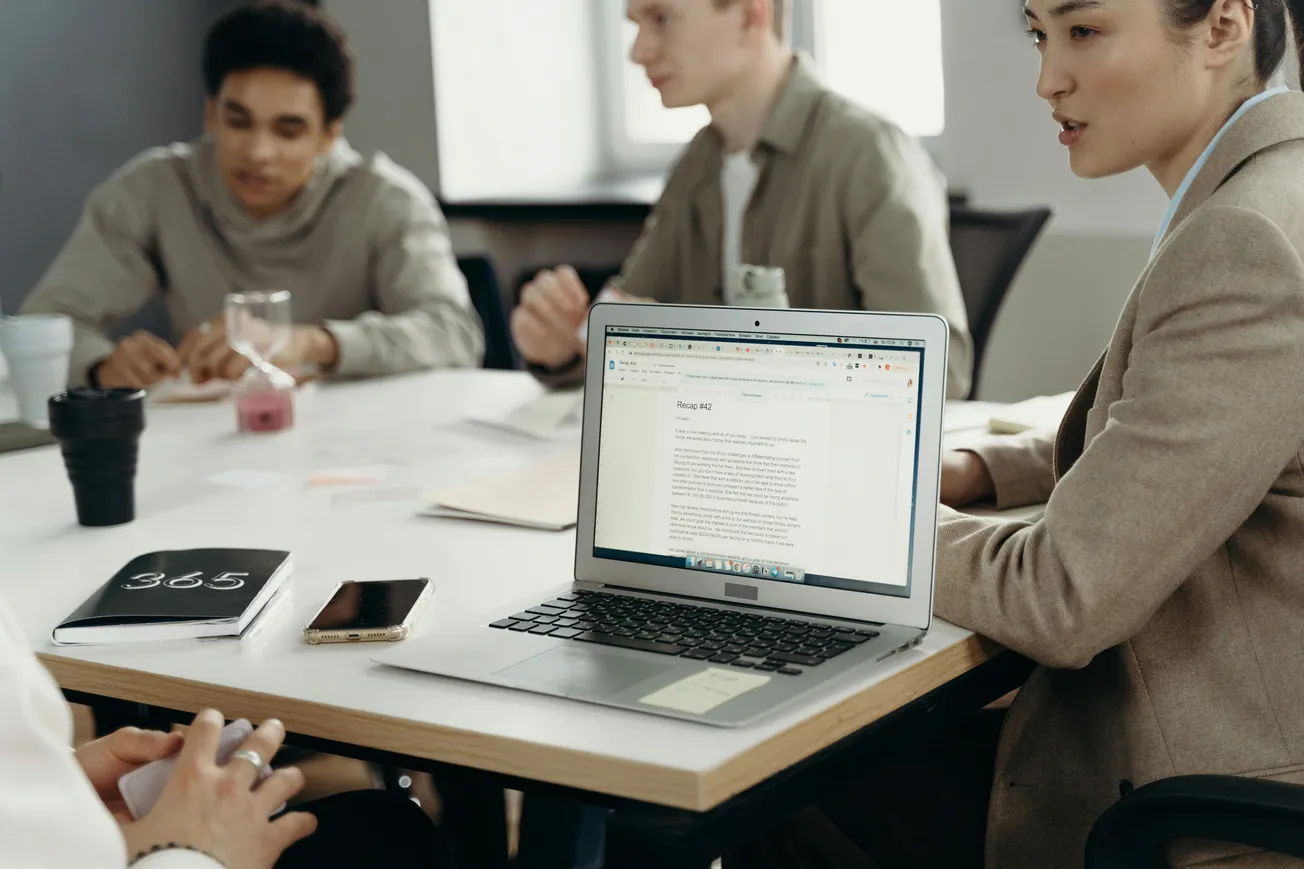 Team meeting with laptop open on a table, showing business notes and planning documents.