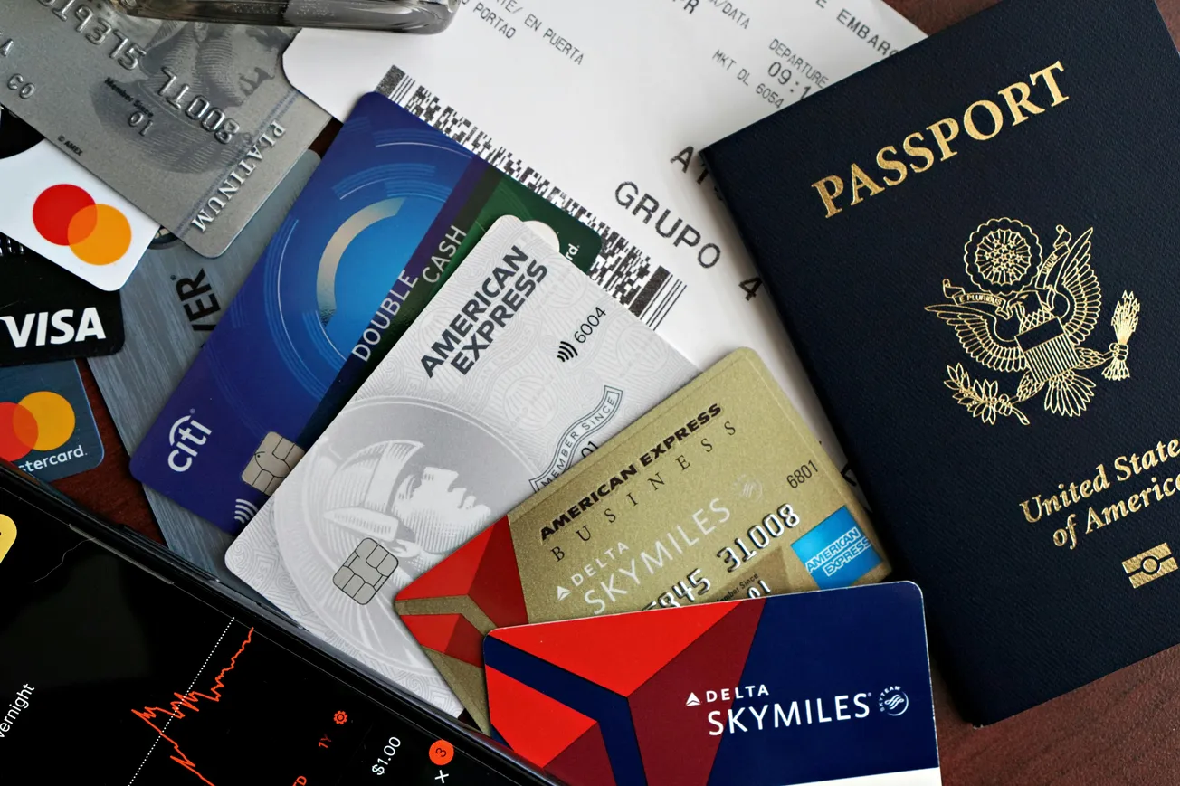 A collection of various credit cards, a smartphone, and a U.S. passport arranged on a surface, conveying themes of travel and financial planning.
