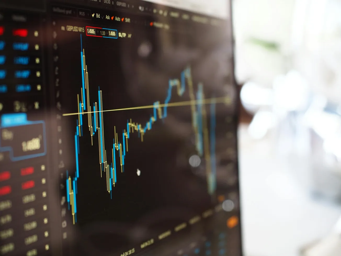 A close-up of a computer screen displaying a candlestick chart with fluctuating lines and financial data, conveying a dynamic market analysis scene.