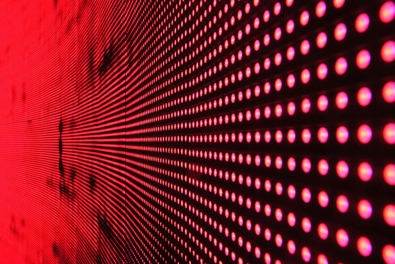 Abstract image of red LED lights in a grid pattern, creating a sense of depth and motion as they recede into darkness.
