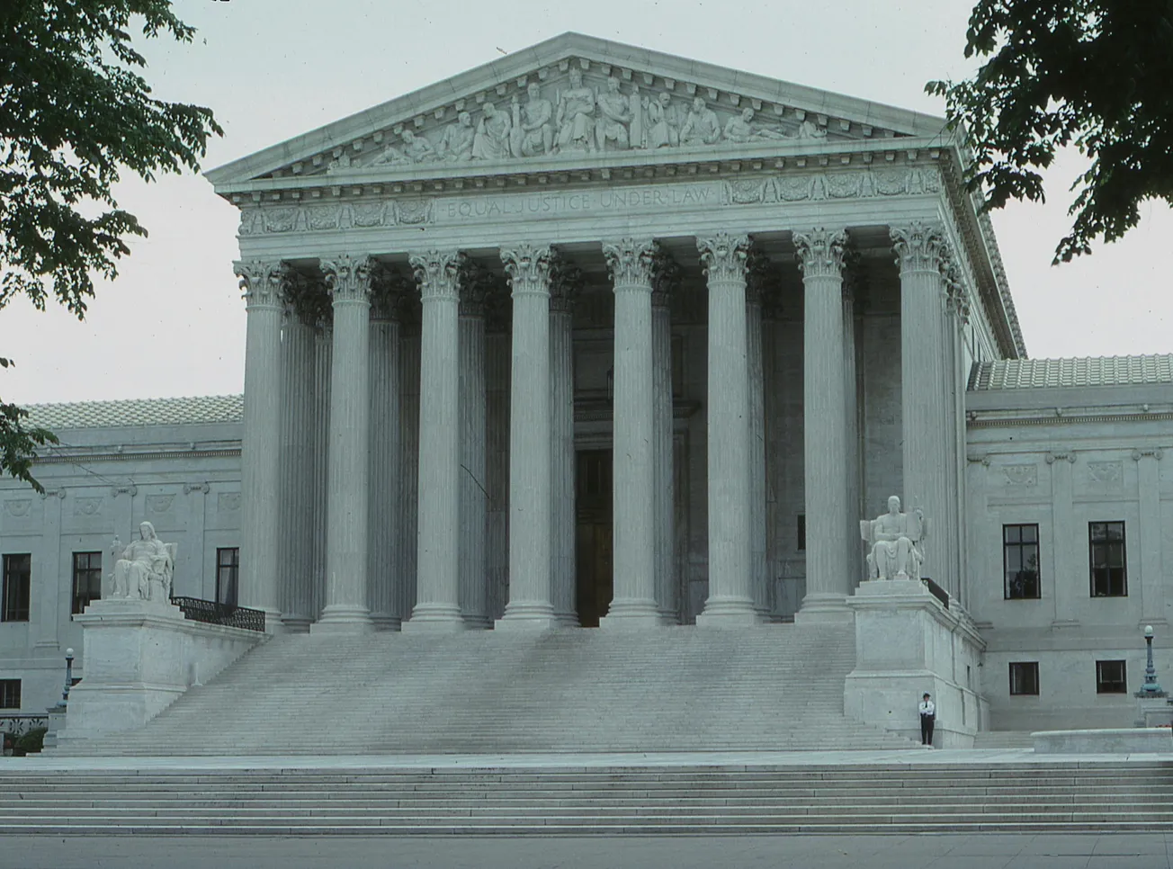 The image shows the front of the U.S. Supreme Court Building, featuring its grand neoclassical facade with tall columns, steps, and sculptures, conveying a sense of authority and justice.
