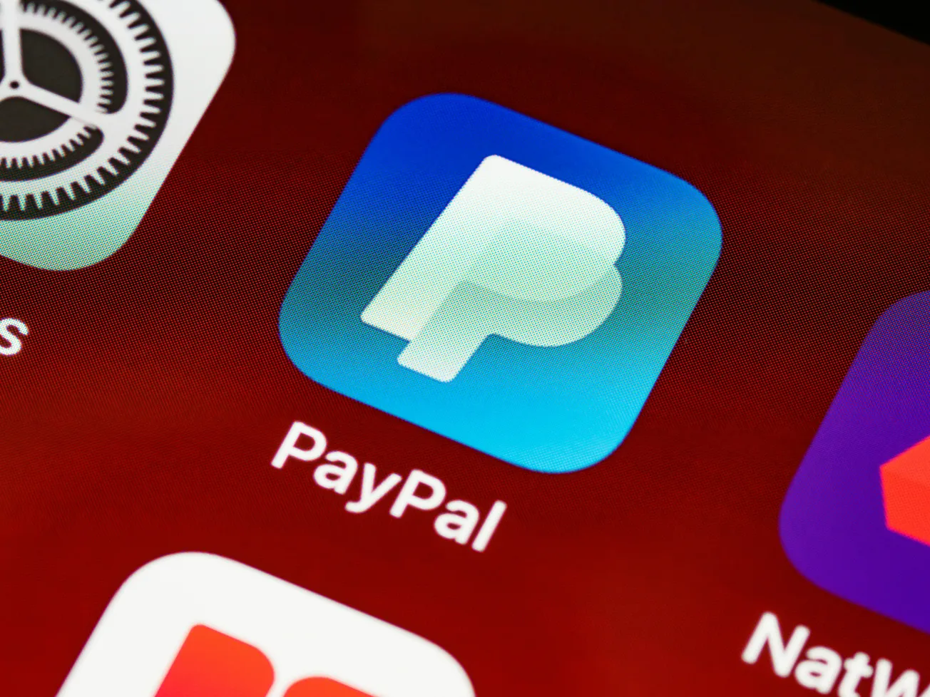 Close-up of smartphone screen showing the PayPal app icon, featuring a stylized "P" on a blue background, indicating a finance-related application.