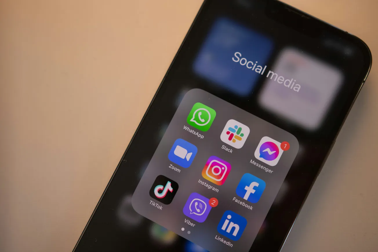 Smartphone screen displaying a folder labeled "Social Media" with apps like WhatsApp, Slack, Messenger, Zoom, Instagram, Facebook, TikTok, Viber, LinkedIn.