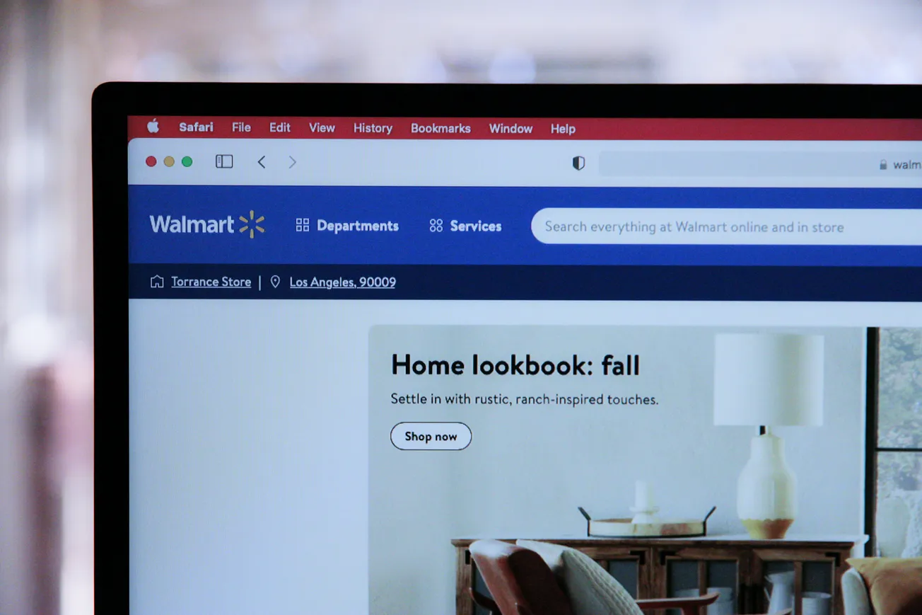 Close-up of a computer screen displaying the Walmart website homepage. The banner promotes a "Home lookbook: fall" with rustic decor.