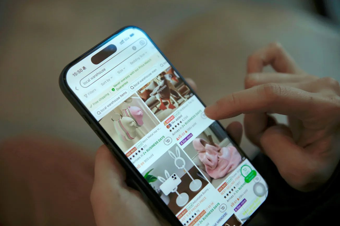 A person scrolling through an online shopping app on a smartphone, browsing various whimsical home decor items, including animal-themed lamps and ornaments.